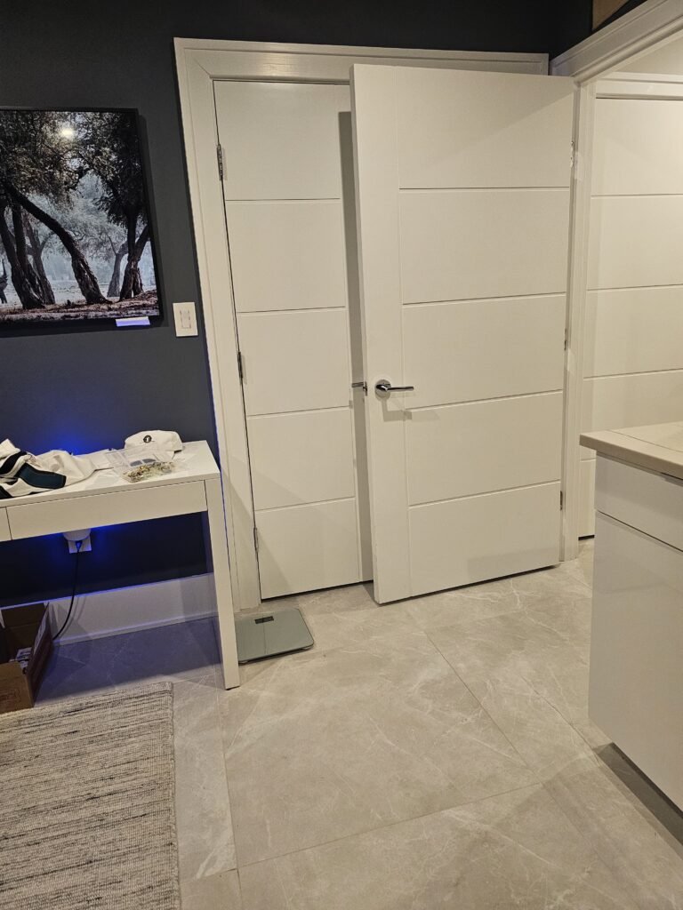 Finished room with large porcelain floor tile, white panel doors and gray walls